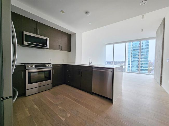 Kitchen with a sink, light countertops, stainless steel appliances, a peninsula, and light wood-type flooring | Image 5