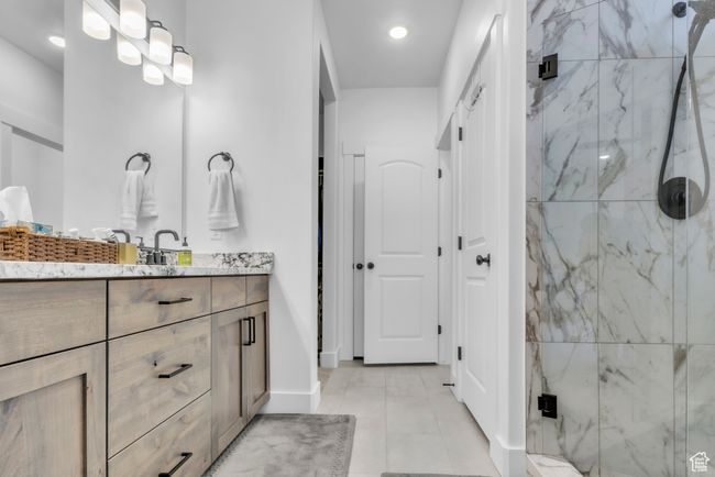 Full bathroom featuring a marble finish shower, vanity, recessed lighting, and tile patterned flooring | Image 20