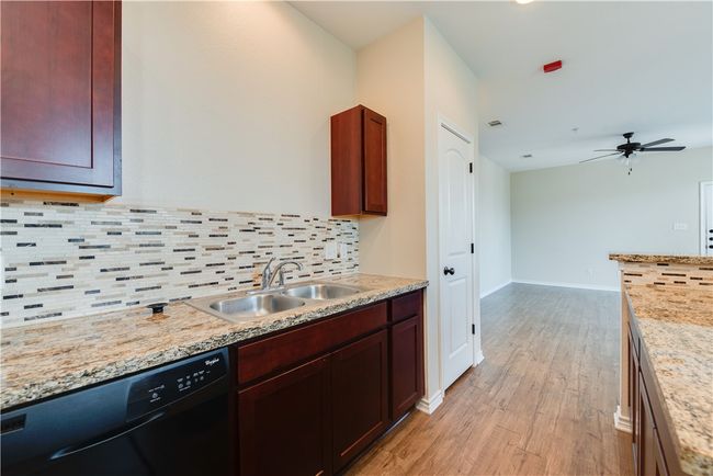 Kitchen with light wood finished floors, a sink, backsplash, a ceiling fan, and dishwasher | Image 5