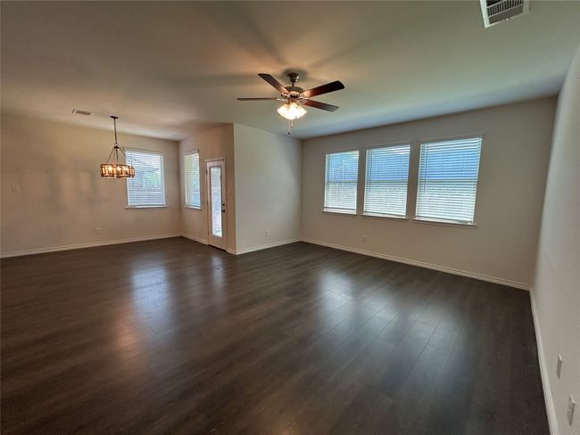 Empty room featuring a chandelier, a ceiling fan, baseboards, and dark wood finished floors | Image 21