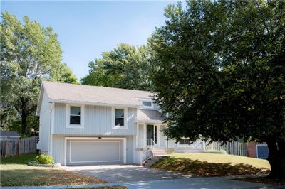 Tri-level home featuring a front yard, a garage, and covered porch | Image 1