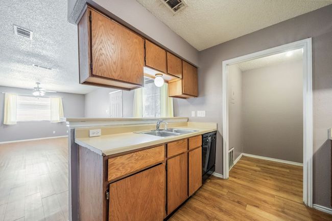 Kitchen featuring a textured ceiling, light countertops, light wood-type flooring, dishwasher, and brown cabinets | Image 15