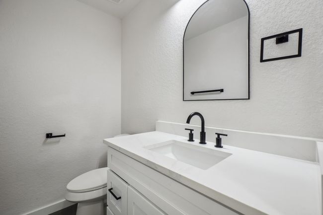Bathroom with vanity, a textured wall, toilet, and baseboards | Image 32