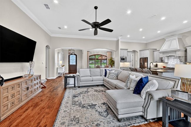 Living area featuring arched walkways, ceiling fan, recessed lighting, wood finished floors, and ornamental molding | Image 9
