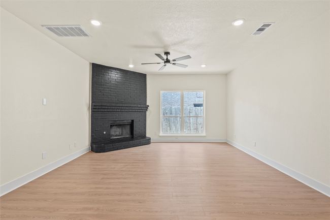 Unfurnished living room featuring ceiling fan, a brick fireplace, light wood-type flooring, and recessed lighting | Image 11