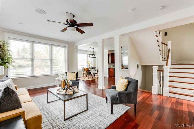 Living area with ornate columns, ceiling fan, wood finished floors, and stairway | Image 19