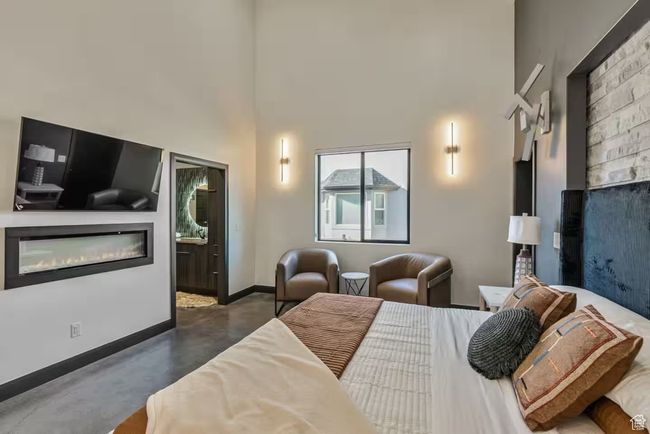 Bedroom with a towering ceiling, baseboards, concrete flooring, and a glass covered fireplace | Image 20