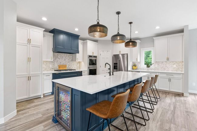 This custom kitchen includes a extra large island with farmhouse sink, beverage fridge, pantry, custom hood vent, quartz counter top, and beautiful fixtures. | Image 5