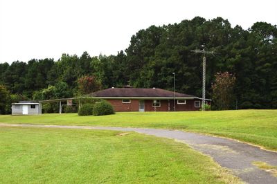 View of front of home featuring a front yard, a carport, and an outdoor structure | Image 2