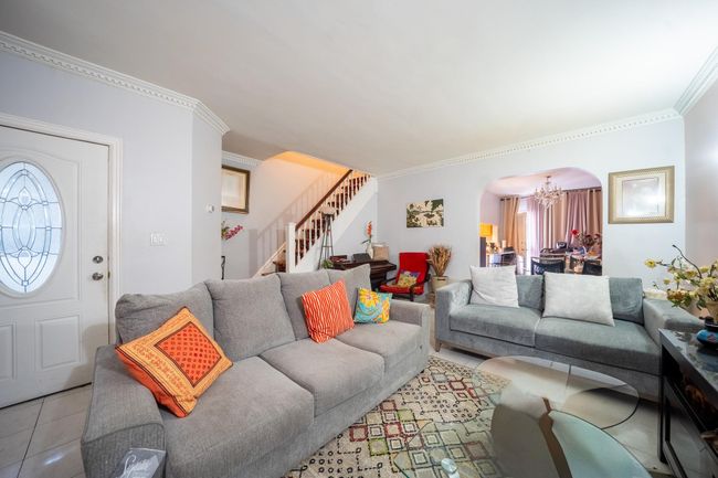 Tiled living room featuring arched walkways, stairway, a chandelier, and ornamental molding | Image 6