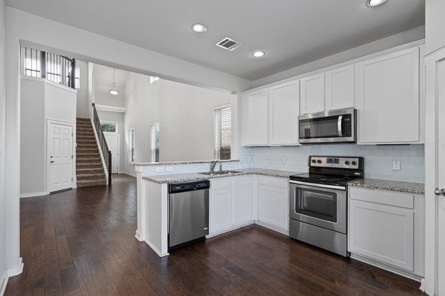 Kitchen with appliances with stainless steel finishes, tasteful backsplash, recessed lighting, a peninsula, and white cabinetry | Image 16