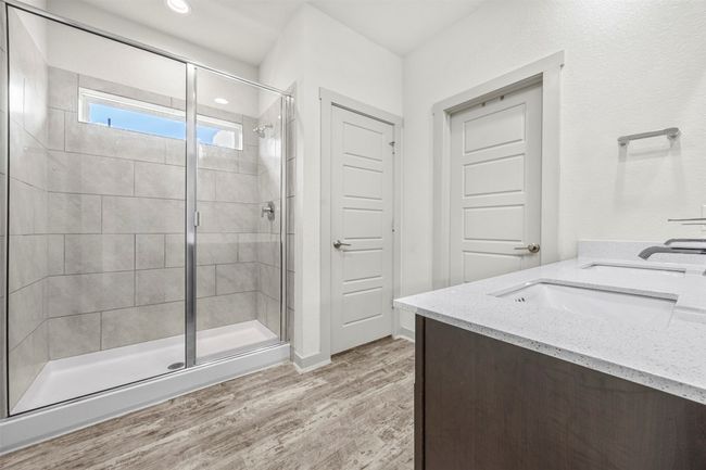 The primary bathroom, complete with a modern dual-sink vanity with quartz countertops and a large, tile-surround walk-in shower. | Image 16