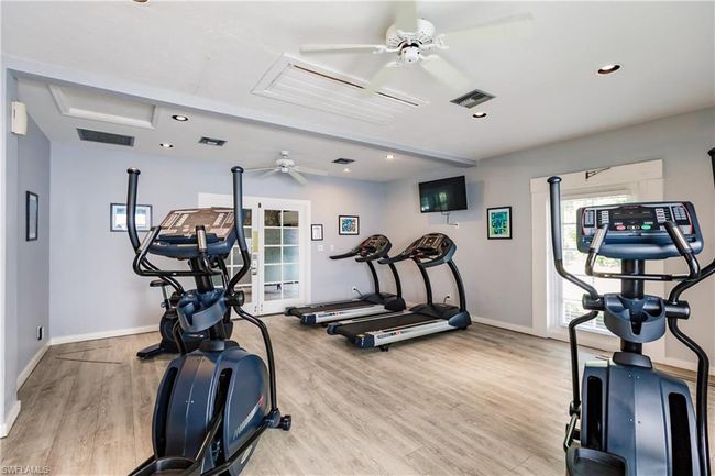 Workout area featuring baseboards, a ceiling fan, wood finished floors, and visible vents | Image 33