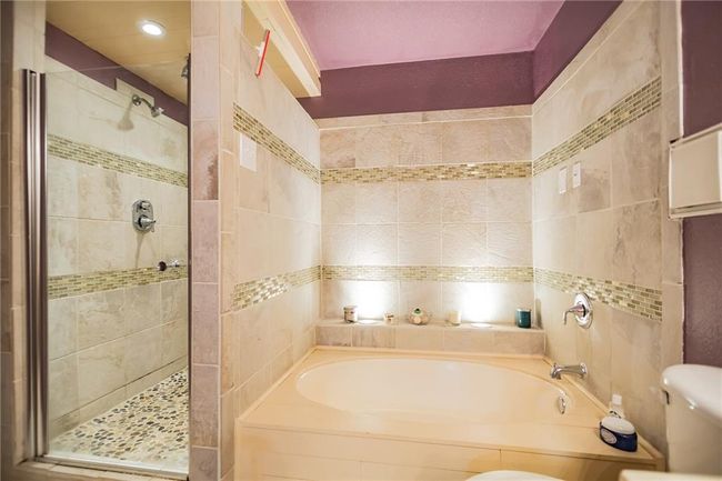 Bathroom featuring a shower stall, a garden tub, toilet, and tile walls | Image 17