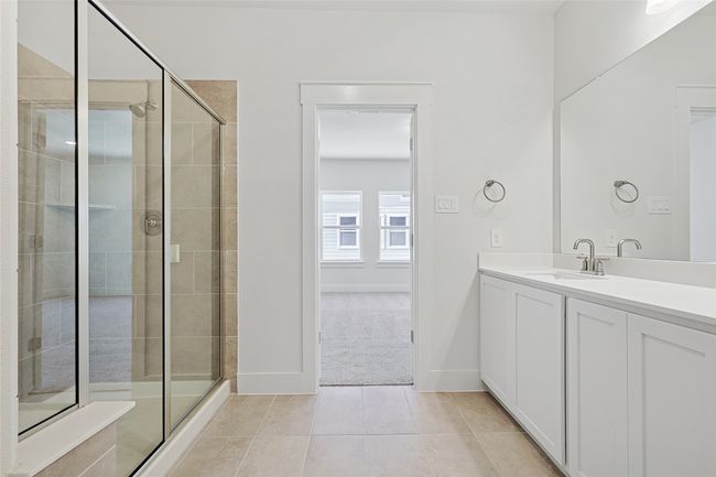 Bathroom with an enclosed shower, vanity, and tile patterned flooring | Image 22