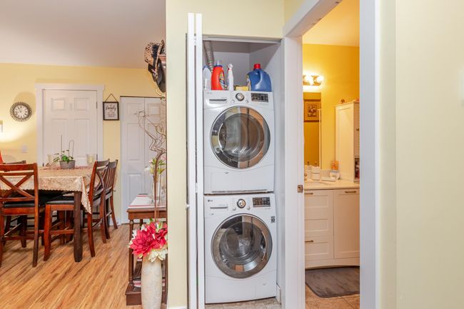 Laundry area featuring stacked washing machine and dryer and light wood-style floors | Image 28