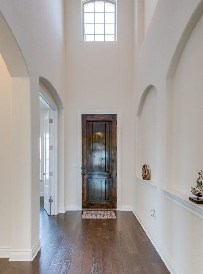 Entryway featuring baseboards, arched walkways, a towering ceiling, and wood finished floors | Image 5