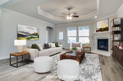 Living room featuring light hardwood / wood-style floors, crown molding, a raised ceiling, and ceiling fan | Image 3