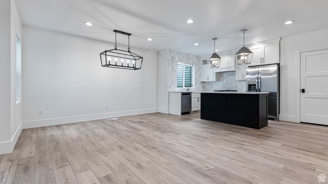 Kitchen with a center island, light countertops, baseboards, and appliances with stainless steel finishes | Image 60