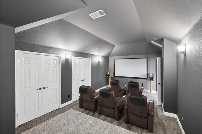 Cinema featuring lofted ceiling, baseboards, visible vents, and carpet flooring | Image 9