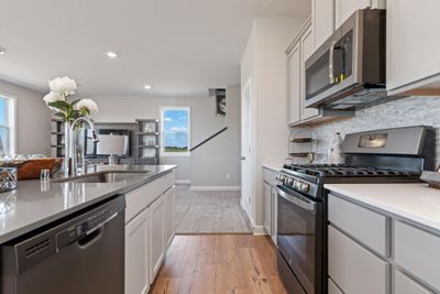 (Photos of model, finishes may vary) The kitchen island and dining area adjacent to the kitchen. Perfect for entertaining or having a family meal together. | Image 3