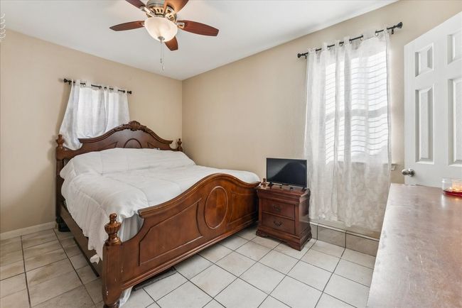 Bedroom with baseboards, a ceiling fan, and light tile patterned floors | Image 16