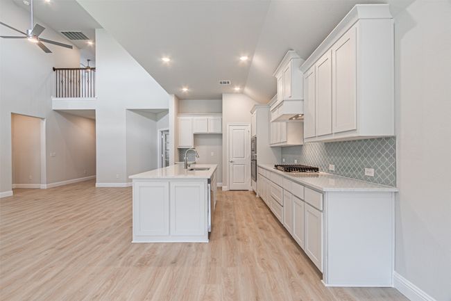 Kitchen with light countertops, white cabinets, backsplash, light wood-style floors, and a ceiling fan | Image 18