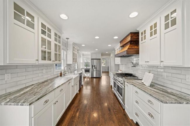 Kitchen featuring tasteful backsplash, stainless steel appliances, and white cabinets | Image 9
