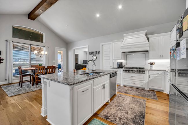 Kitchen featuring white cabinetry, sink, an island with sink, custom range hood, and appliances with stainless steel finishes | Image 10