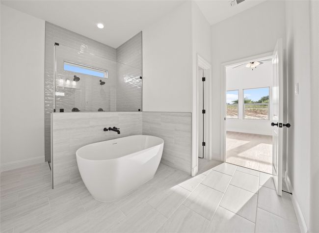 Bathroom with a walk in shower, a freestanding tub, baseboards, and tile patterned floors | Image 22