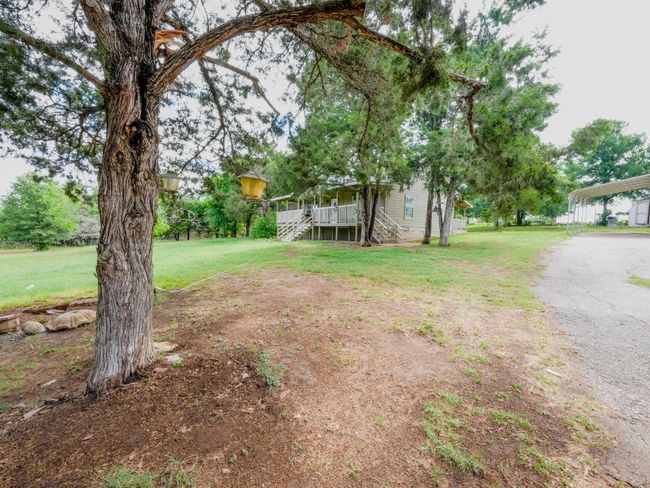 View of green lawn featuring a carport, stairway, and a porch | Image 6