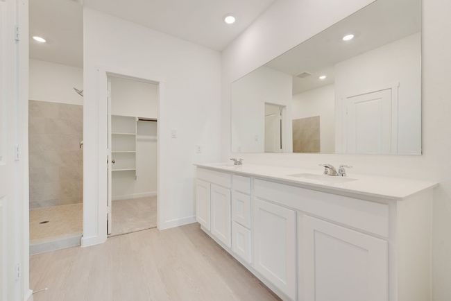 Full bathroom with double vanity, wood finished floors, tiled shower, recessed lighting, and a walk in closet | Image 22