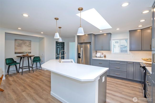 Huge island with Quartz Counters and plenty of seating - pretty pendant lights ensure a very bright eating area. | Image 9