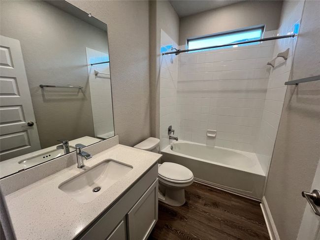 Bathroom featuring wood finished floors, vanity, shower combination, and a textured wall | Image 10