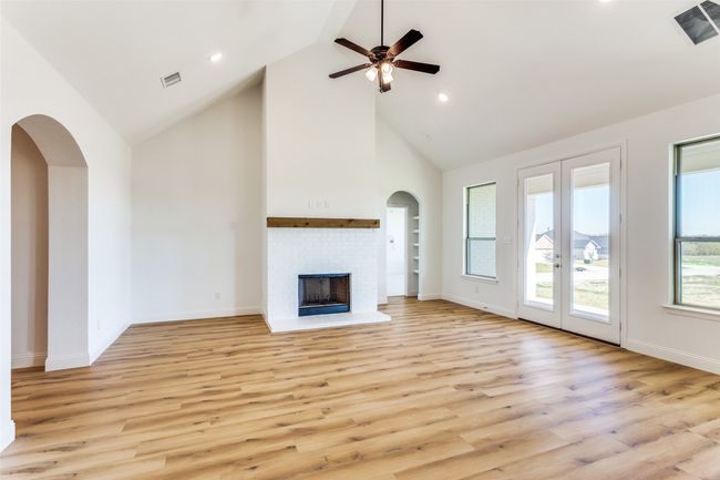 Unfurnished living room with high vaulted ceiling, light hardwood / wood-style floors, a fireplace, and ceiling fan | Image 6
