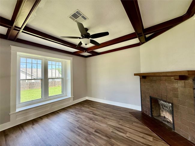 Unfurnished living room with coffered ceiling, dark wood-style flooring, a fireplace, beamed ceiling, and a ceiling fan | Image 6