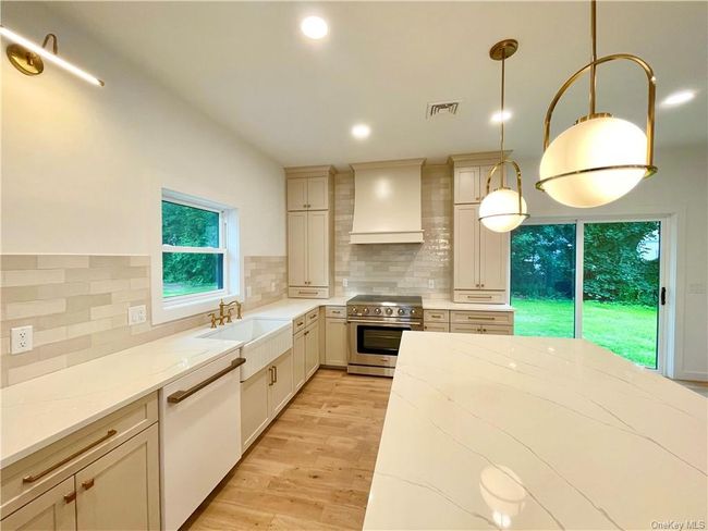 Example of the work we do. Not this house. Kitchen with sink, hanging light fixtures, premium range hood, high end range, and dishwasher | Image 7