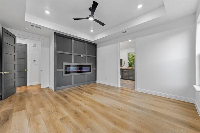 Unfurnished living room featuring light hardwood / wood-style floors, ceiling fan, and a tray ceiling | Image 25