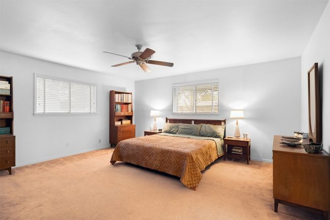 Bedroom featuring a ceiling fan, baseboards, and light colored carpet | Image 29
