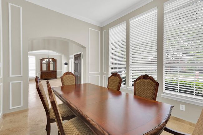 Dining room featuring arched walkways, a notable chandelier, and ornamental molding | Image 8