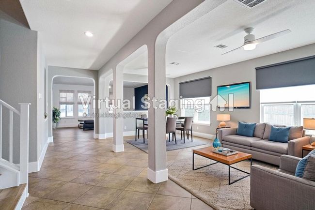 Virtual Staged Living area with visible vents, baseboards, arched walkways, and tile patterned floors | Image 7