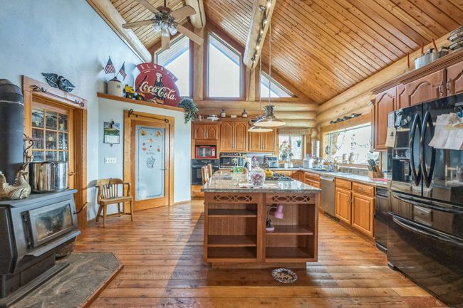 Kitchen with black appliances, open shelves, high vaulted ceiling, wood ceiling with exposed beams, and hardwood / wood-style flooring | Image 29