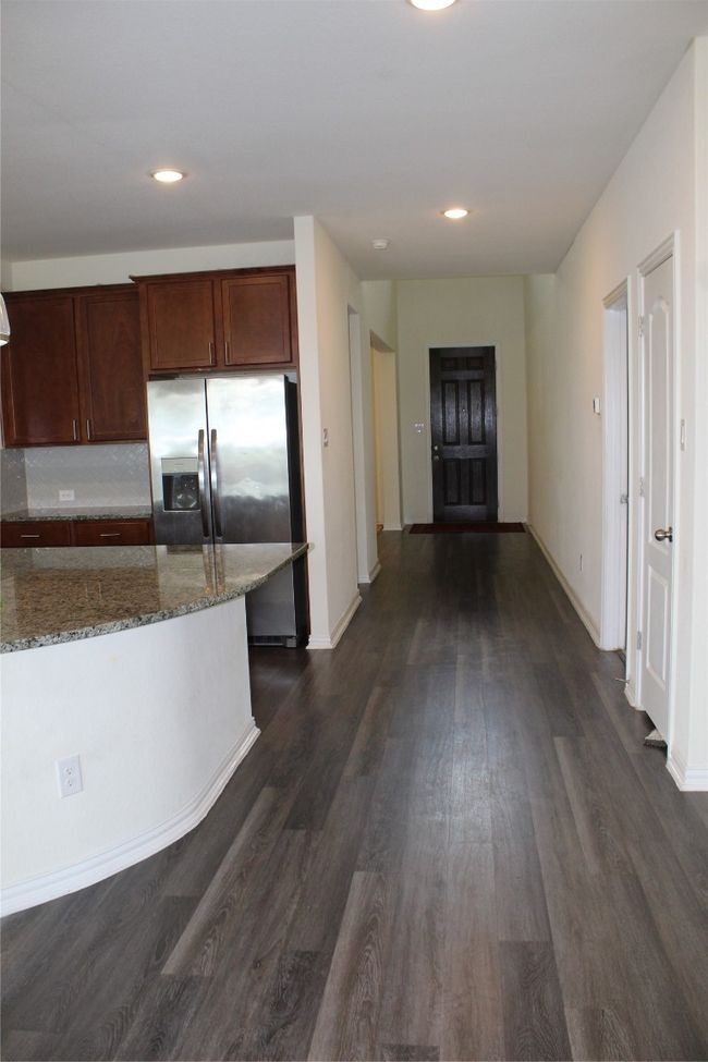 Kitchen featuring stone countertops, dark wood-style floors, refrigerator, baseboards, and recessed lighting | Image 12