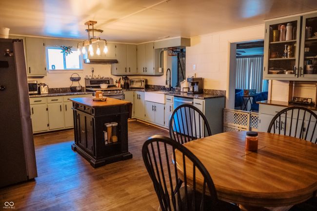 kitchen featuring dark wood-style floors, a kitchen island, dark countertops, stainless steel appliances, and a sink | Image 24
