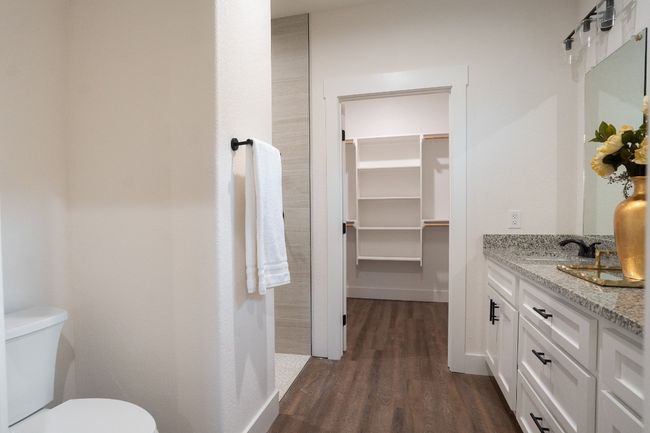 Bathroom with wood finished floors, vanity, toilet, a spacious closet, and baseboards | Image 22