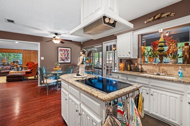 Kitchen featuring white cabinets, black electric cooktop, a sink, a textured ceiling, and dark wood-style flooring | Image 8