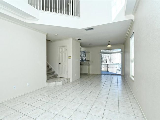 Unfurnished living room featuring visible vents, a high ceiling, ornamental molding, and light tile patterned floors | Image 6