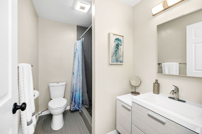 Full bathroom with toilet, a tiled shower with curtain, vanity, and baseboards | Image 22