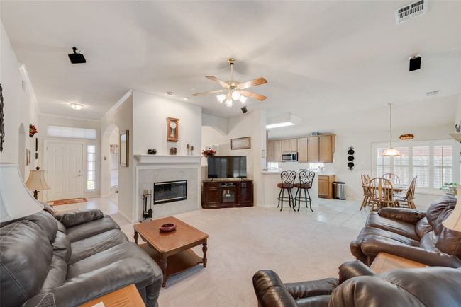 Living room with plenty of natural light, ceiling fan, a premium fireplace, and light tile patterned flooring | Image 11