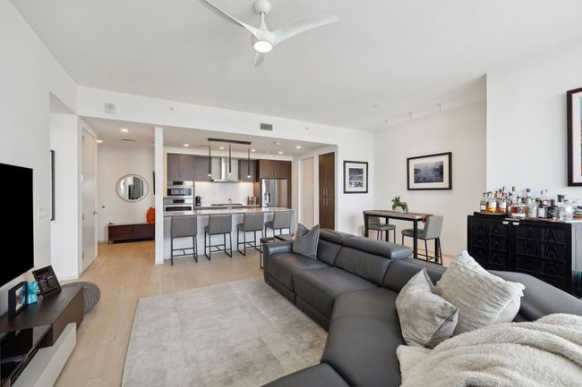 Living room featuring light wood-style floors, ceiling fan, and a bar | Image 15